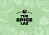 A light green background with white line drawings of vegetables and herbs framing the central logo and text for 'The Spice Lab'. Produktbild-Vorschau