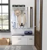 An entryway with a coat rack, bench, mirror, and basket. Voir les images du produit
