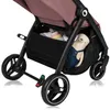 Close-up view of the lower part of a pink stroller, showing the storage basket with a teddy bear and some items inside, and the wheels. Produktbild-Vorschau