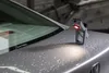 A small LED work light is placed on the trunk of a car with water droplets on it. Podgląd zdjęcia produktu