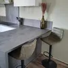 A modern kitchen counter with two bar stools and a vase of dried flowers. Anteprima dell’immagine prodotto