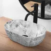 A marble sink with a black faucet on a wooden countertop, with a mirror in the background. Produktbild-Vorschau