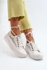 A pair of white lace sneakers with white laces tied around the ankles, worn by a person wearing light yellow cropped pants. Voir les images du produit