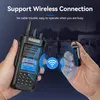 A person is holding a walkie-talkie and a small Bluetooth earpiece, with a graphic indicating a wireless connection between them. Podgląd zdjęcia produktu