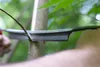 A close-up shot of a person using a curved knife to trim a branch from a tree. Podgląd zdjęcia produktu