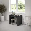 A modern compact desk with a stool tucked underneath, positioned in front of a window with a view of greenery. A chair is placed to the right of the desk. Anteprima dell’immagine prodotto