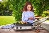 A woman is grilling skewers outdoors on a sunny day. Produktbild-Vorschau