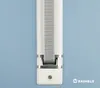 A close-up view of a white roll-up blind strap mechanism mounted on a light blue wall. Produktbild-Vorschau