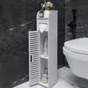 A white bathroom storage unit with an open door, placed next to a toilet. The unit contains shelves with various items, including toilet paper, bottles, and jars. A small plant and a bottle are on top. Náhled obrázku produktu