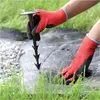 A person wearing red gloves is using a black harpoon peg to secure black landscape fabric in a garden setting. Náhled obrázku produktu