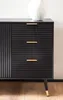 A close-up view of a black sideboard with gold handles and legs. Voir les images du produit