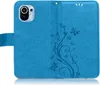 A blue flip phone case with a floral and butterfly embossed design is shown open, revealing the inside. Produktbild-Vorschau