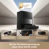 A robotic vacuum cleaner and its charging/emptying station are shown in a modern, minimalist setting, with feature callouts below. Produktbild-Vorschau