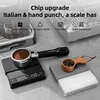 Two digital scales for coffee, one black and one white, with coffee grounds and a portafilter. The background shows parts of a coffee machine. Produktbild-Vorschau