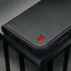 A close-up shot of a black leather phone case with red stitching and a red bull logo. Voir les images du produit