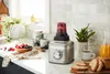 A KitchenAid blender with a red smoothie in the cup sits on a kitchen counter next to a bowl of berries, a mug of coffee, and sliced bread. Voir les images du produit