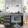 A modern vanity table with a large mirror, drawers, and a stool, set in a well-lit room with windows. Náhled obrázku produktu