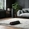 A power strip is placed on a rug in a living room setting with a sofa and a speaker in the background. Náhled obrázku produktu