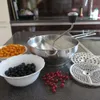 A kitchen counter with a food mill, bowls of berries, and sieve attachments. Anteprima dell’immagine prodotto