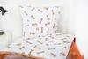 A close-up view of a white duvet cover and pillowcase with a brown bone and paw print pattern, laid out on a bed. Anteprima dell’immagine prodotto