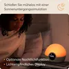 A woman is in bed, looking down at a bedside lamp that simulates a sunset. Produktbild-Vorschau