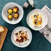 A table setting with bowls of yogurt and fruit, apples, and bread. Produktbild-Vorschau