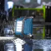 A blue work light is illuminated and placed on a wet surface during a rain shower. Voir les images du produit