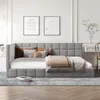 A modern bedroom or living room setting featuring a gray upholstered daybed with several decorative pillows and a throw blanket. Produktbild-Vorschau