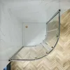 A top-down view of a modern corner shower enclosure with a curved glass door and a white shower tray, set against a marble wall and a wooden floor. Produktbild-Vorschau