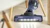 A blue Bosch Serie 4 vacuum cleaner is shown cleaning a wooden floor. Voir les images du produit