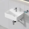 A white ceramic wall-mounted sink with a chrome faucet and drainpipe, mounted on a white tiled wall. A silver soap dish with a blue bar of soap is attached to the wall to the right of the sink. Anteprima dell’immagine prodotto