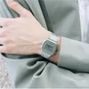 A close-up shot of a person's wrist wearing a silver digital watch, with the person's arm resting on a light gray suit jacket. Voir les images du produit