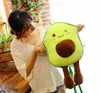 A woman is holding a plush avocado toy. Produktbild-Vorschau