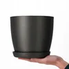 A hand holding a dark gray plant pot with a saucer. Produktbild-Vorschau