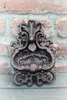 A vintage-style cast iron door knocker mounted on a brick wall. Produktbild-Vorschau