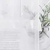 A close-up view of a white sheer curtain with text printed on it, with a potted plant in the background. Produktbild-Vorschau