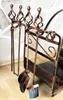 A fireplace tool set and log holder are displayed against a stone wall and wooden floor. Podgląd zdjęcia produktu