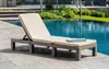 A chaise lounge with a cushion and a folded towel sits on a patio next to a swimming pool. Voir les images du produit
