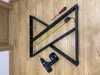 Two black metal table legs are laid out on a wooden floor with a screwdriver, a tape measure, and a drill. Anteprima dell’immagine prodotto