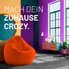 A modern living room with a large orange beanbag chair in the foreground and colorful walls. Voir les images du produit