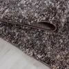 A close-up view of a shaggy rug with a marbled brown, gray, and white pattern, folded over to reveal the backing. Náhled obrázku produktu