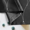 A close-up view of a black curtain with a white geometric pattern, with three blueberries in the foreground. Produktbild-Vorschau