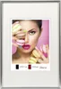 A woman holding macarons in front of a pink background, framed by a silver photo frame. Produktbild-Vorschau