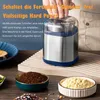 A hand pressing down on the lid of a coffee grinder, with ground coffee and flour in bowls in the foreground. Produktbild-Vorschau