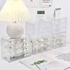 A desk setup with a lamp, a digital timer, a mini calendar, and several clear plastic drawer organizers filled with various small items. Produktbild-Vorschau