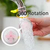 A hand holding a faucet attachment that sprays water. Produktbild-Vorschau