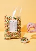 A hand is picking up a snack from a small bowl of snacks, with a large bag of snacks in the background. Produktbild-Vorschau