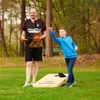 A man and a boy playing cornhole in a grassy park. Produktbild-Vorschau