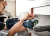 A person is using a cordless drill to screw something into a cabinet or drawer. Produktbild-Vorschau