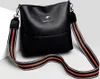 A black handbag with a striped strap is displayed against a light gray background. Náhľad obrázku produktu